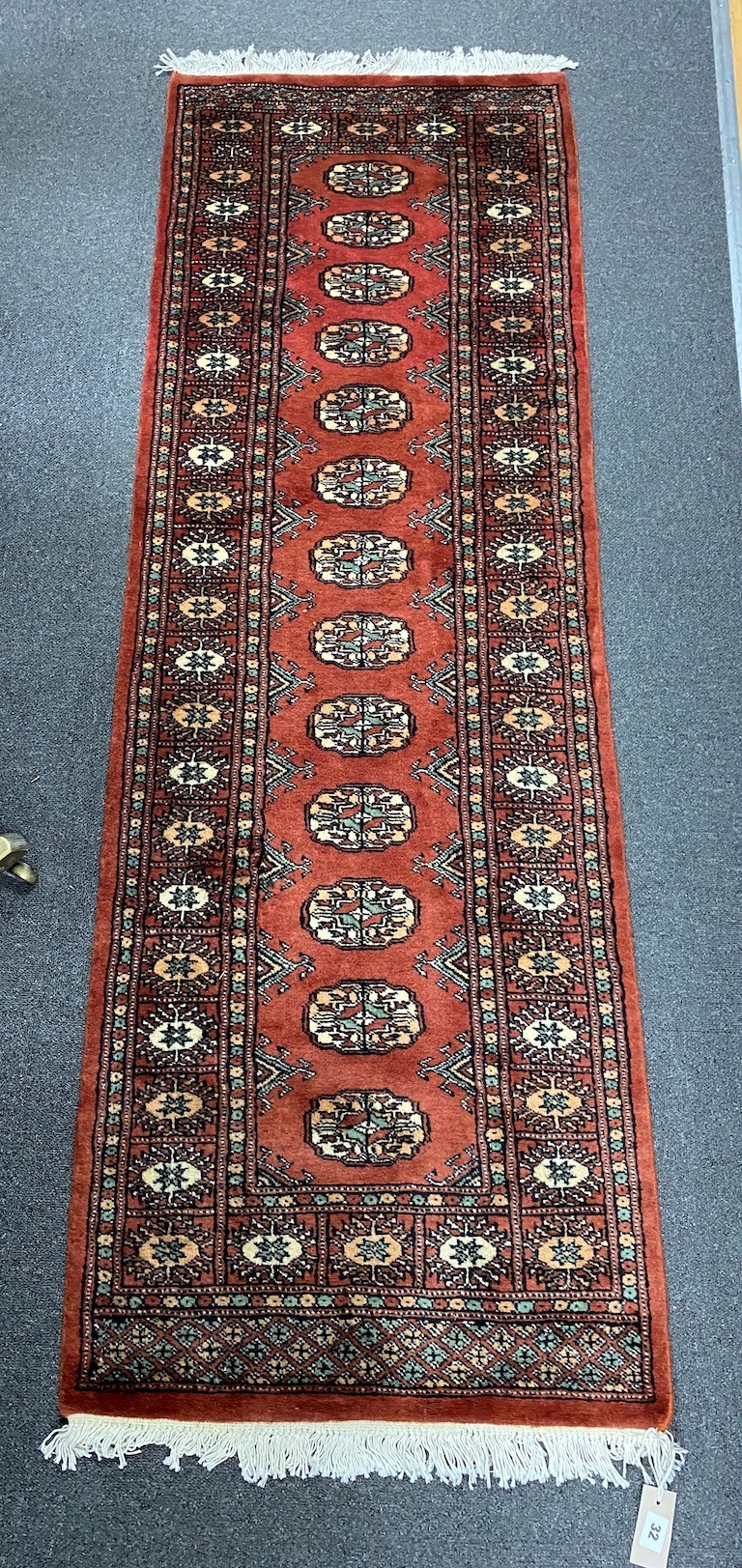 A Bokhara style red ground rug, 190 x 62cm